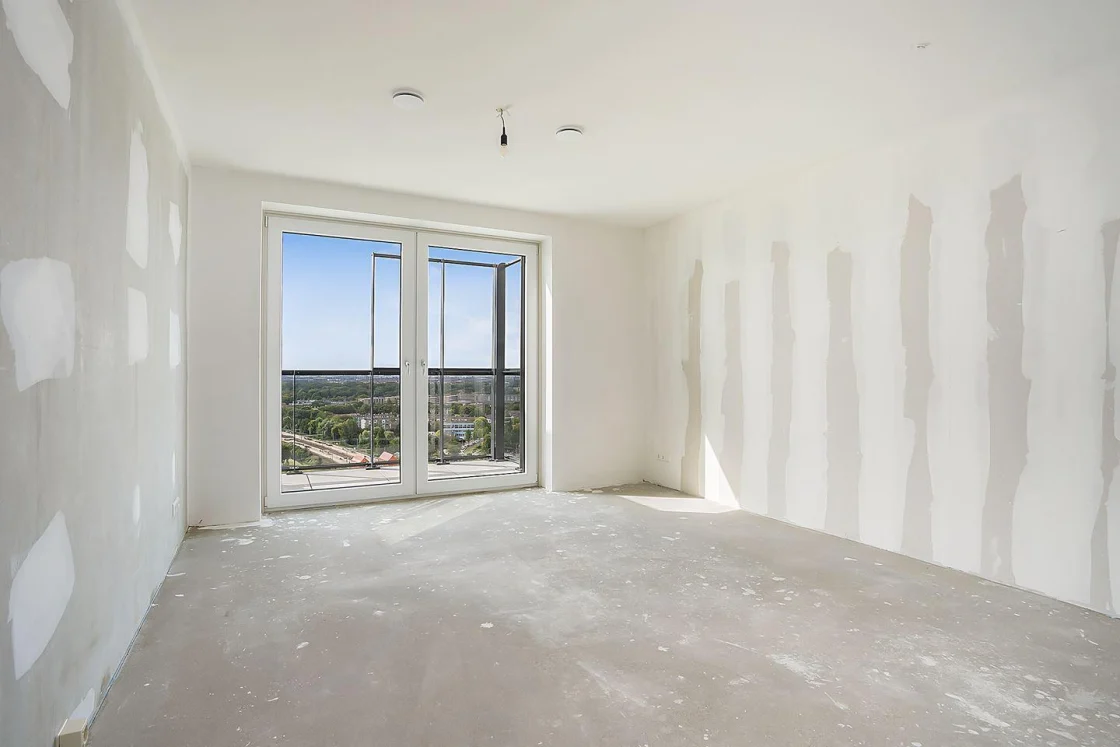 Empty new-build room with no kitchen, bare walls and a concrete floor